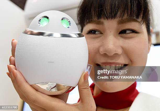 This photo taken on October 3, 2016 shows a staffer from the Sharp booth introducing a prototype robot called "Home Assistant", which has the ability...