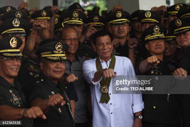 Philippine President Rodrigo Duterte gestures with raised fists with military officers during a "talk to the troops" visit in Manila on October 4,...