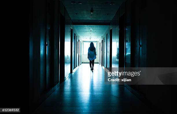 young woman  in dark building walkway - threats stockfoto's en -beelden