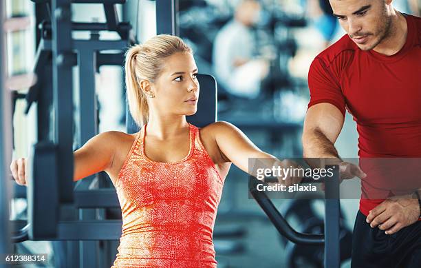 woman exercising in a gym with an instructor. - flirting gym stock pictures, royalty-free photos & images