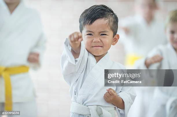 cute little boy taking karate - taekwondo stock-fotos und bilder