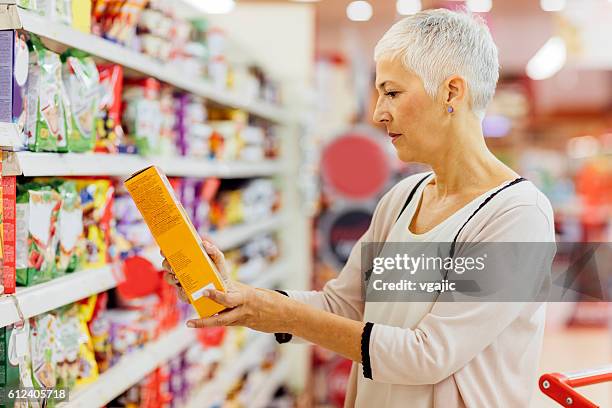 reife frau lebensmittel einkaufen. - frühstücksflocken stock-fotos und bilder