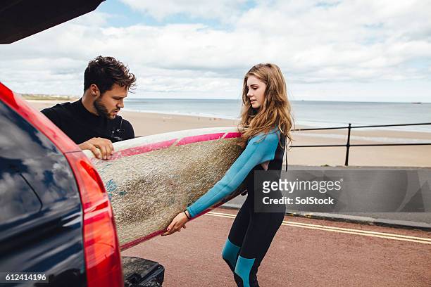 surfers unloading surf boards from car - wetsuit stock pictures, royalty-free photos & images