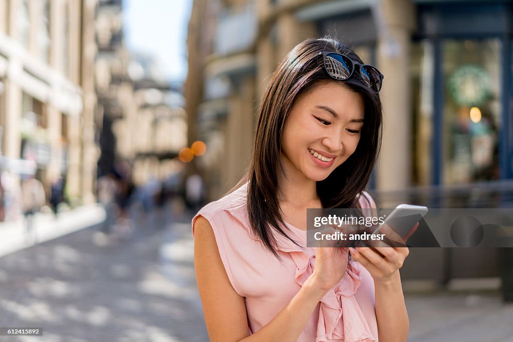 Asian woman using her mobile phone outdoors