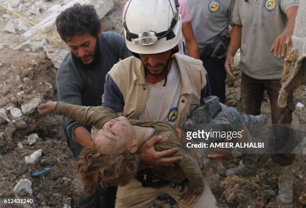 Syrian civil defence volunteer, known as the White Helmets, holds the body of a child after he was pulled from the rubble following a government...