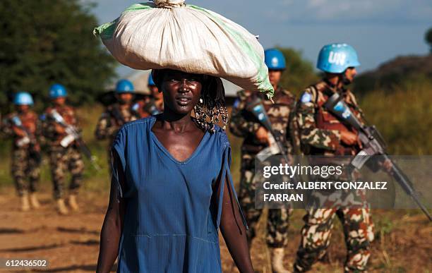 Displaced woman carries goods as United Nations Mission in South Sudan peacekeepers patrol outside the premises of the UN Protection of Civilians...