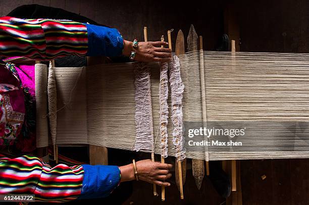 tibetan woman dressed in traditional costume making hand-woven cloth at home - yunnan stock-fotos und bilder