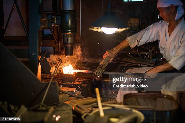 japanese blacksmith pounds red hot steel while forging a sword - samurai sword stock pictures, royalty-free photos & images