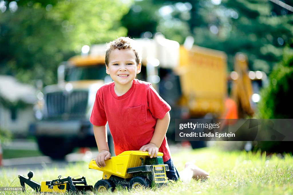 Portrait of special needs boy playing with his toy trucks