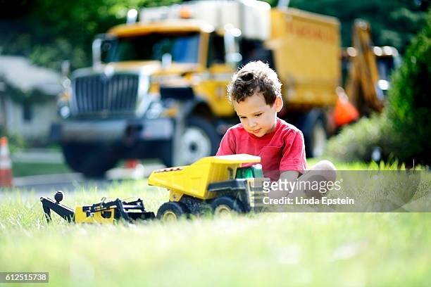 boy with adhd focuses his concentration on toy construction trucks - boy yellow shirt stock pictures, royalty-free photos & images
