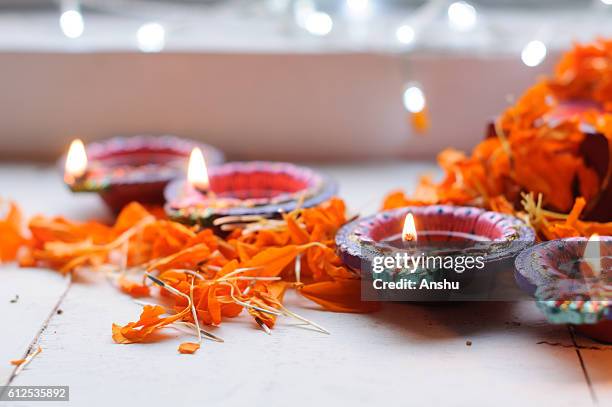 colorful clay diya lamps lit during diwali celebration with flowers - diya oil lamp stock pictures, royalty-free photos & images