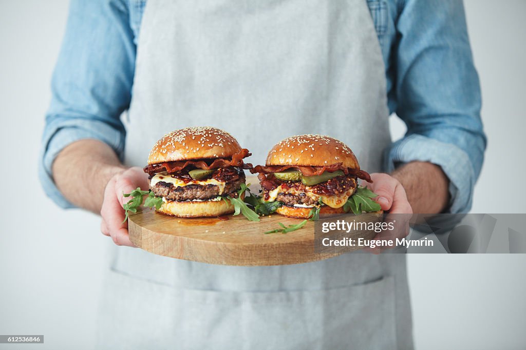 Man holding homemade angus beef burgers with bacon whisky jam