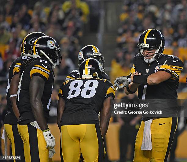 Quarterback Ben Roethlisberger of the Pittsburgh Steelers looks at a play list on his wrist as he huddles with the offense during a game against the...