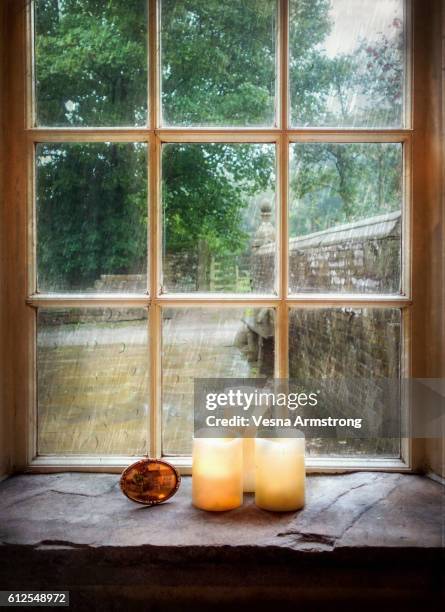 flickering candles on mullion window sill - rain window stock pictures, royalty-free photos & images