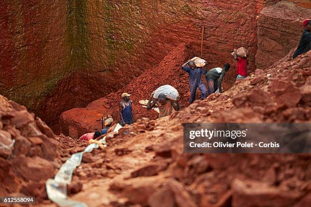 Miners carry bags filled with excess earth out of theirs concession surrounded by hoses pumping out the rain water from their plots 28 March 2013...