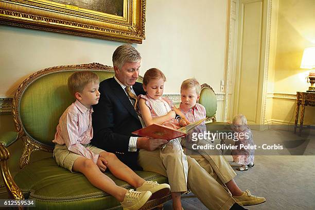 Prince Philippe of Belgium reads a book to his children : Gabriel, Elisabeth, Emmanuel, and Eleonore, in the music room of the royal castle of Laeken.