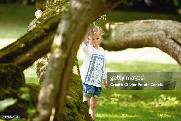 Princess Elisabeth peering from under a tree in the garden of the royal castle of Laeken.