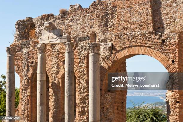 columns and wall inside the greek theatre, and view of golfo di naxos, taormina, sicily, italy - naxos sicily stock-fotos und bilder