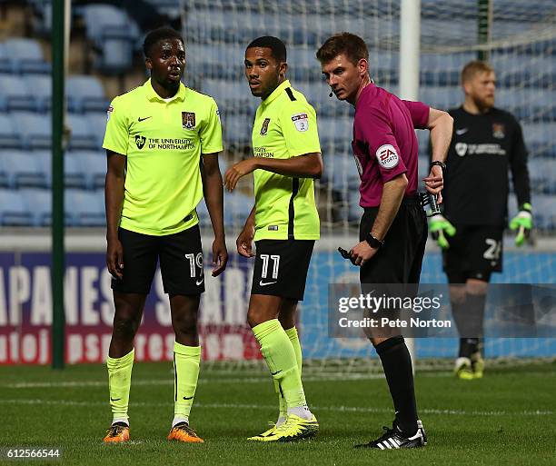 Emmanuel Sonupe and Kenji Gorre of Northampton Town line up to defend a free kick as referee Ollie Yates looks on during the EFL Checkatrade Trophy...