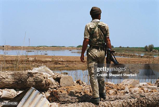 An Iraqi soldier holding an AK-47 rifle surveys the marshes of the Fao Peniunsula during the war when Iraq recaptured the peninsula from Iran.