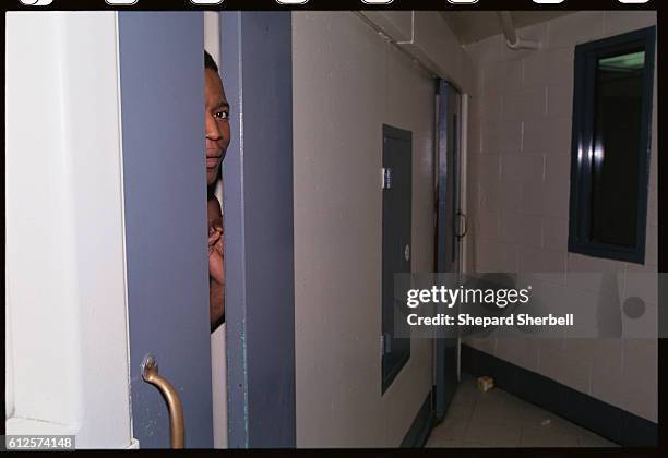 An African American inmate peers through an opening in his prison cell in the Buckingham Correctional Institution. | Location: Dillwyn, Virginia, USA.