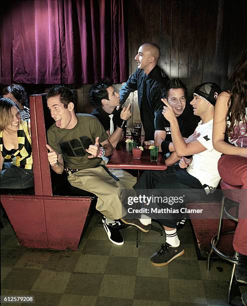 The punk rock group Simple Plan sit flirting with women in a booth : Chuck Comeau , Pierre Bouvier , Jeff Stinco , David Desrosiers , and Sebastien...