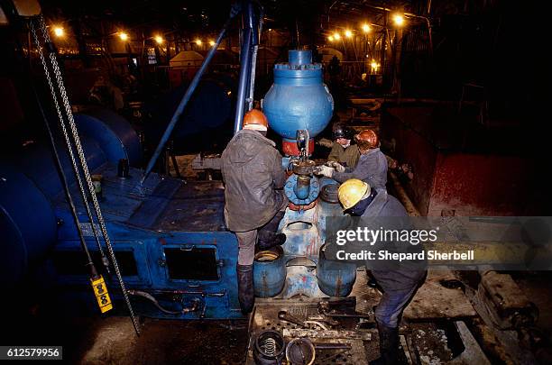 Oil workers adjust a large piece of drilling equipment used in a deep oil well project, financed by the Tatneft oil company.