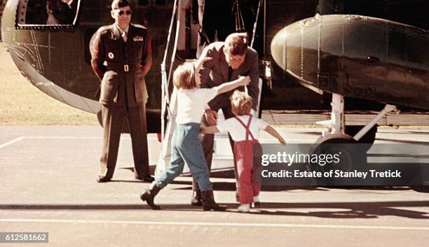 Caroline and John run to welcome their father, American President John F. Kennedy, as he gets out of the helicopter.