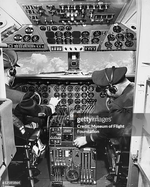 Pilots operate flight controls in the cockpit of an airborne DC-6, ca. 1940s.