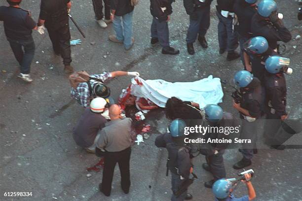 Young protester was shot dead by a member of the carabinieri, during the anti-globalization riots.A group of police encircle the body as it is taken...