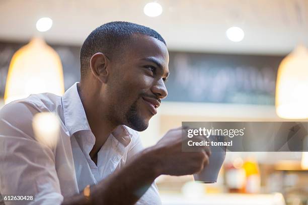 afro-american man enjoying big cup of coffee - think big stockfoto's en -beelden