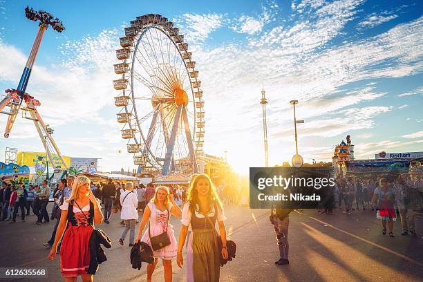 ferris wheel and visitors walking through oktoberfest fairgrounds, munich, germany - 十月啤酒節 個照片及圖片檔