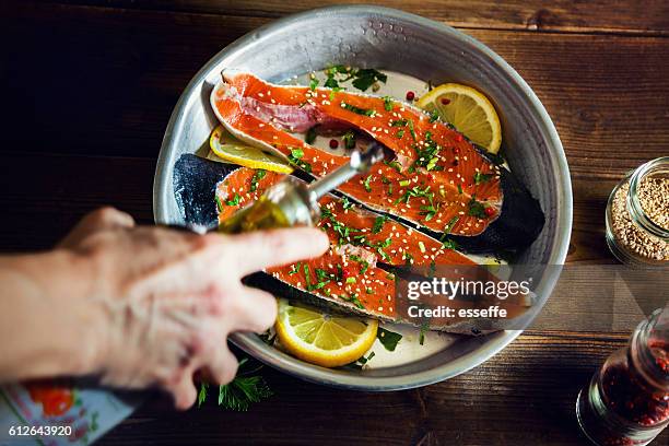 salmon slices seasoned with lemon, sesame oil and parsley - cooking fish stock pictures, royalty-free photos & images