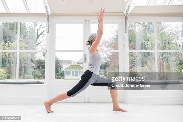 senior woman in yoga post with arms raised - lunge imagens e fotografias de stock
