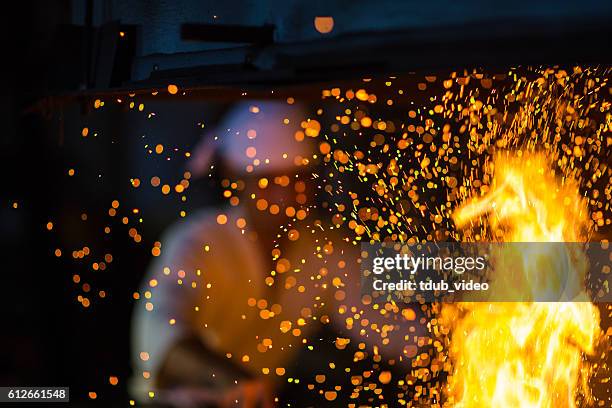 japanese blacksmith stokes a fire preparing to forge a sword - smederij stockfoto's en -beelden