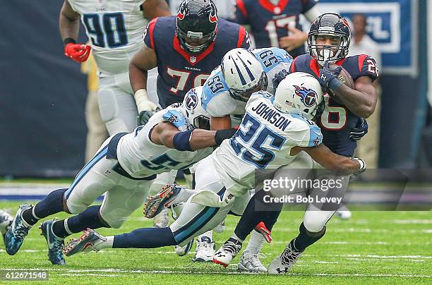 Lamar Miller of the Houston Texans is tackled by Rashad Johnson of the Tennessee Titan, Avery Williamson and Wesley Woodyard at NRG Stadium on...