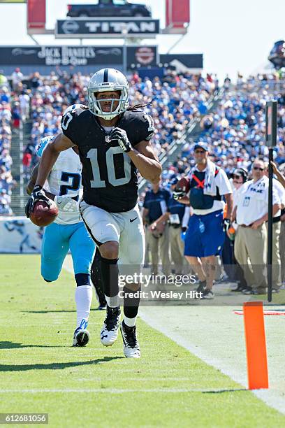 Seth Roberts of the Oakland Raiders runs the ball in for a touchdown while being chased by Brice McCain of the Tennessee Titans at Nissan Stadium on...