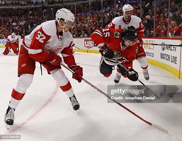 Artem Anisimov of the Chicago Blackhawks gets arborne trying control the puck between Louis-Marc Aubry and Jonathan Ericsson of the Detroit Red Wings...