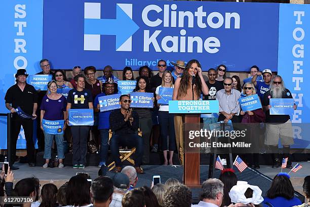 Singer/songwriter John Legend sits onstage as he listens to his wife, model and television personality Chrissy Teigen, speak at a campaign event with...