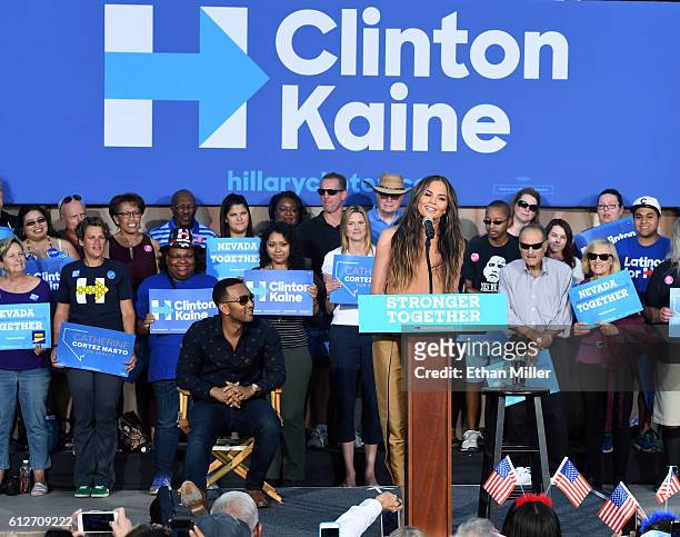 Singer/songwriter John Legend sits onstage as he listens to his wife, model and television personality Chrissy Teigen, speak at a campaign event with...