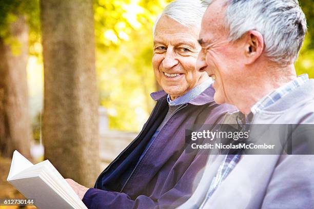 paar von älteren männern teilen geschichten im park - schwuler stock-fotos und bilder