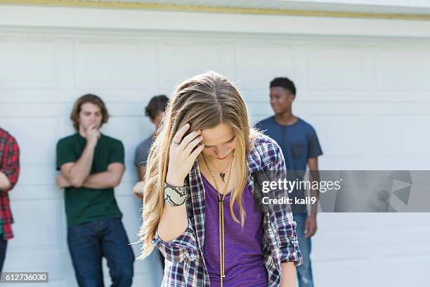 teenage mädchen verärgert blick nach unten, junge männer im hintergrund - black and white sad boy stock-fotos und bilder