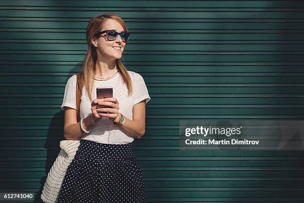 mujer enviando mensajes de texto y sonriendo a alguien - green skirt fotografías e imágenes de stock