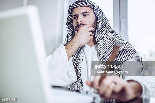 arabische geschäftsmann im büro - addiction mobile and laptop stock-fotos und bilder