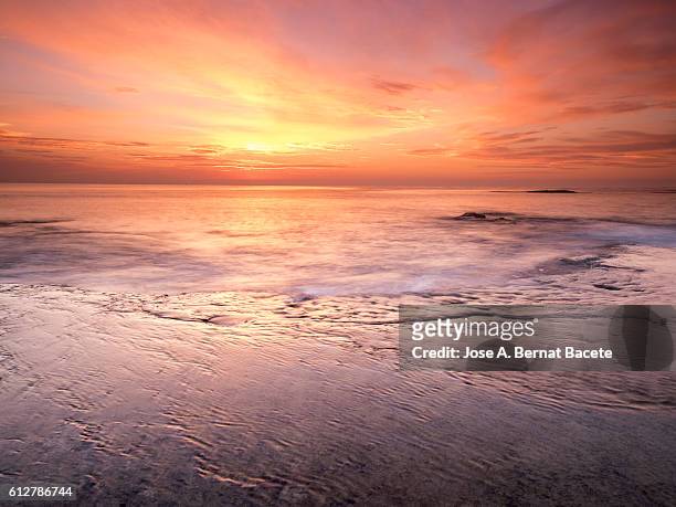 the first light of dawn orange beachfront in an area of coast with rocks and waves in motion - beauty in nature sea imagens e fotografias de stock