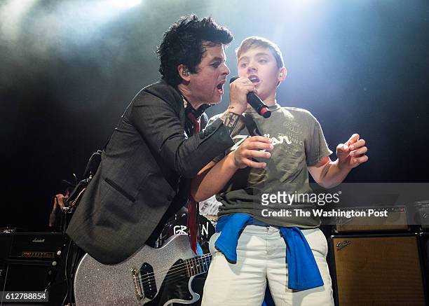 Billie Joe Armstrong of Green Day brings a young fan on stage to sing at their sold out show at the 9:30 Club on Monday.
