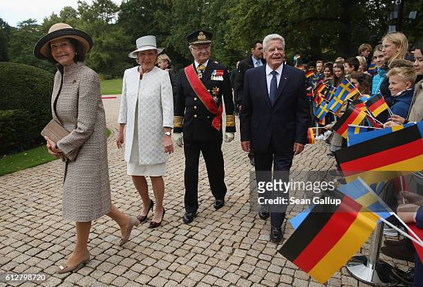 Queen Silvia of Sweden, German First Lady Daniela Schadt, King Carl XVI Gustaf of Sweden and German President Joachim Gauck walk past children upon...