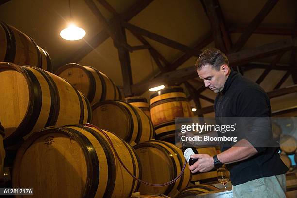 Friedrich Wilhelm Becker, co-owner of the Weingut Friedrich Becker Estate, syphons pinot noir wine from a barrel, also known as spaetburgunder,...