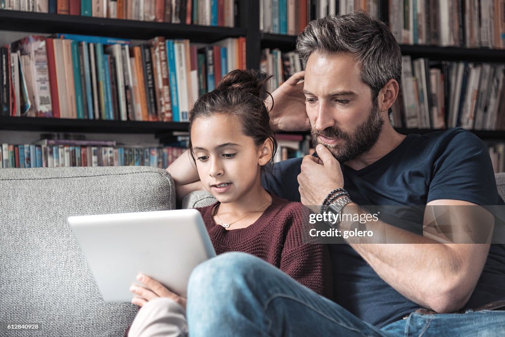 Father and daughter at sofa with digital tablet
