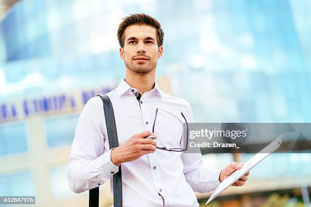 pensive businessman holding financial report - portrait of pensive young businessman wearing glasses stock pictures, royalty-free photos & images